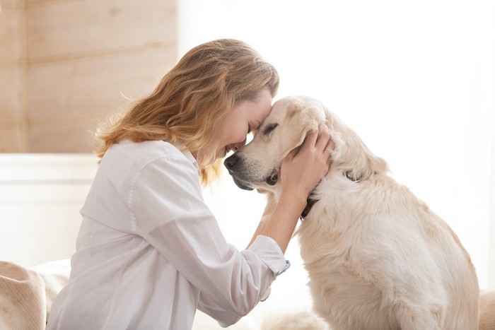 目を閉じておでこを合わせる女性と犬