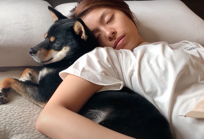 目を閉じた犬と眠る人