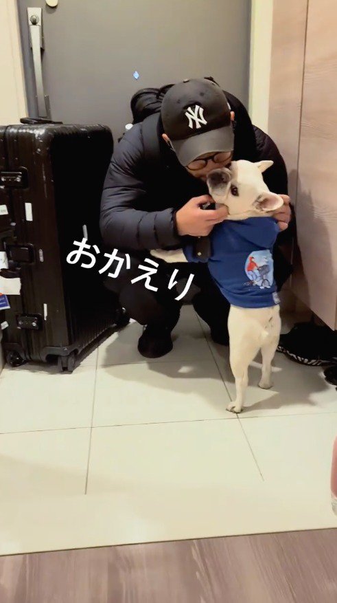 男性に顔を近づけられて目を細める犬