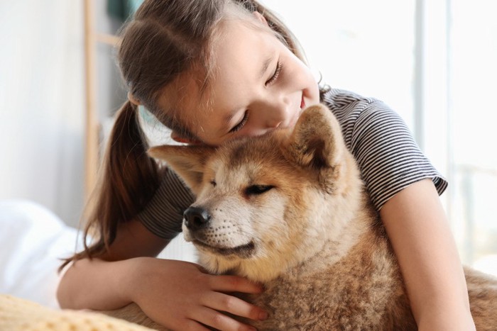 飼い主さんの首元で伏せて寝ているような様子の犬