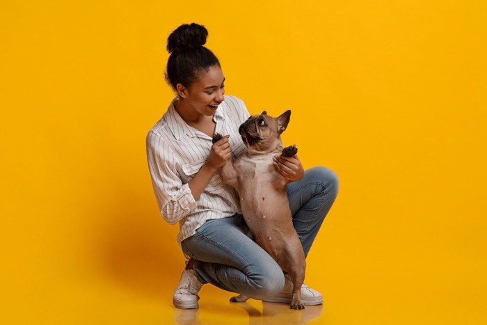 女性笑っている 犬の前足を持ちたっちしているポーズ