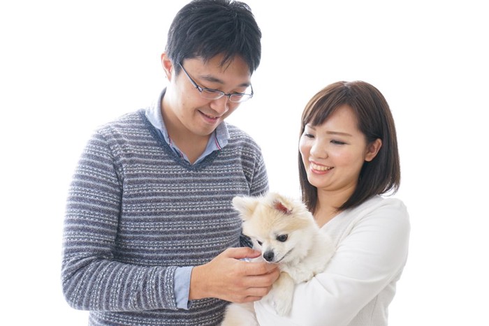 犬を抱く女性と笑顔で撫でる男性