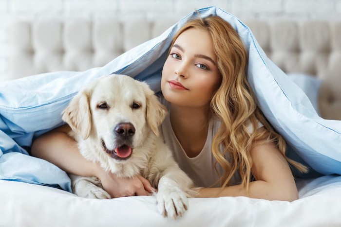 ベッドでくつろぐ飼い主と犬